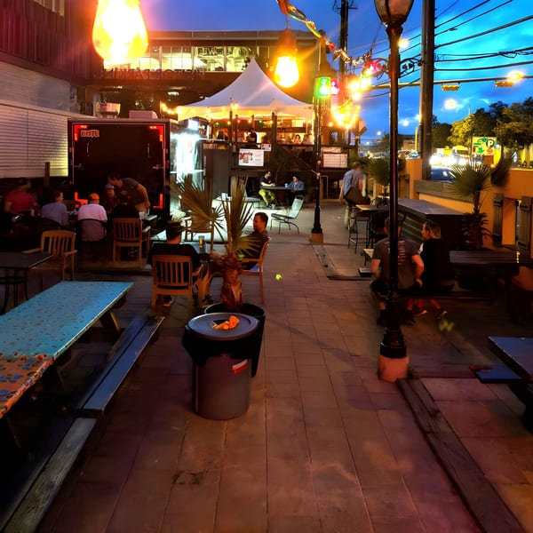 Dusk view of Super Burrito's outdoor patio with people dining under string lights and a tent.