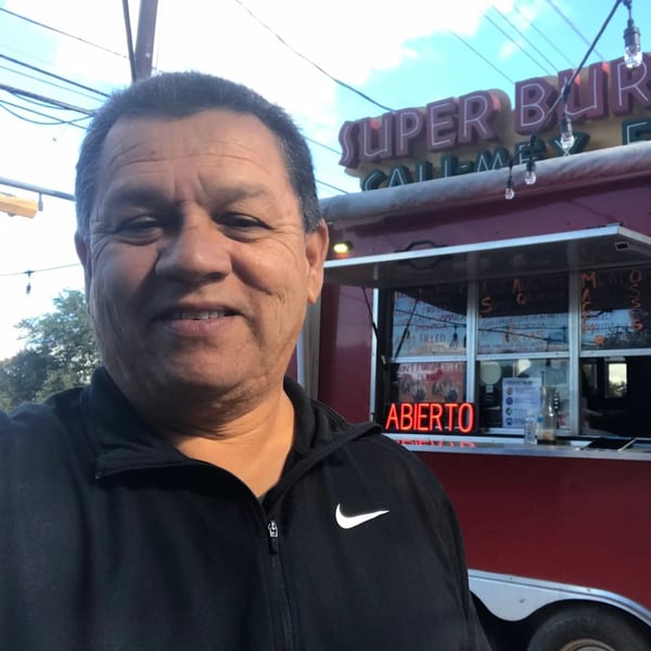 Man in a black jacket smiling in front of the Super Burrito food truck with an "ABIERTO" sign.