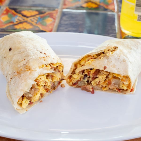 A Super Burrito breakfast burrito, cut in half, revealing scrambled eggs, bacon, and potatoes.