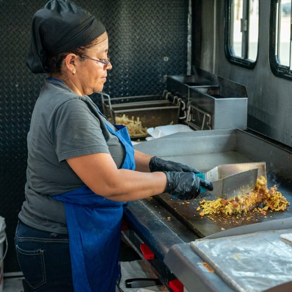A Super Burrito chef in a food truck cooking Mexican food on a griddle.