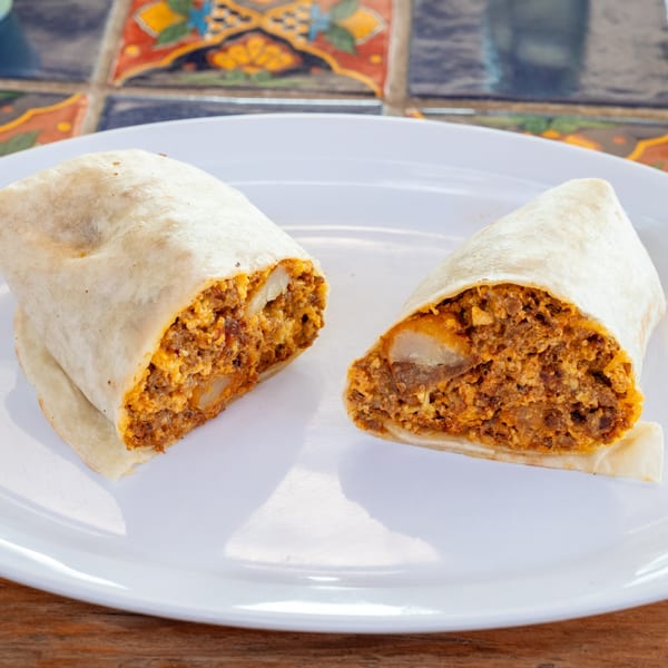 Two halves of a Super Burrito, revealing a hearty filling of chorizo, eggs, and potatoes.